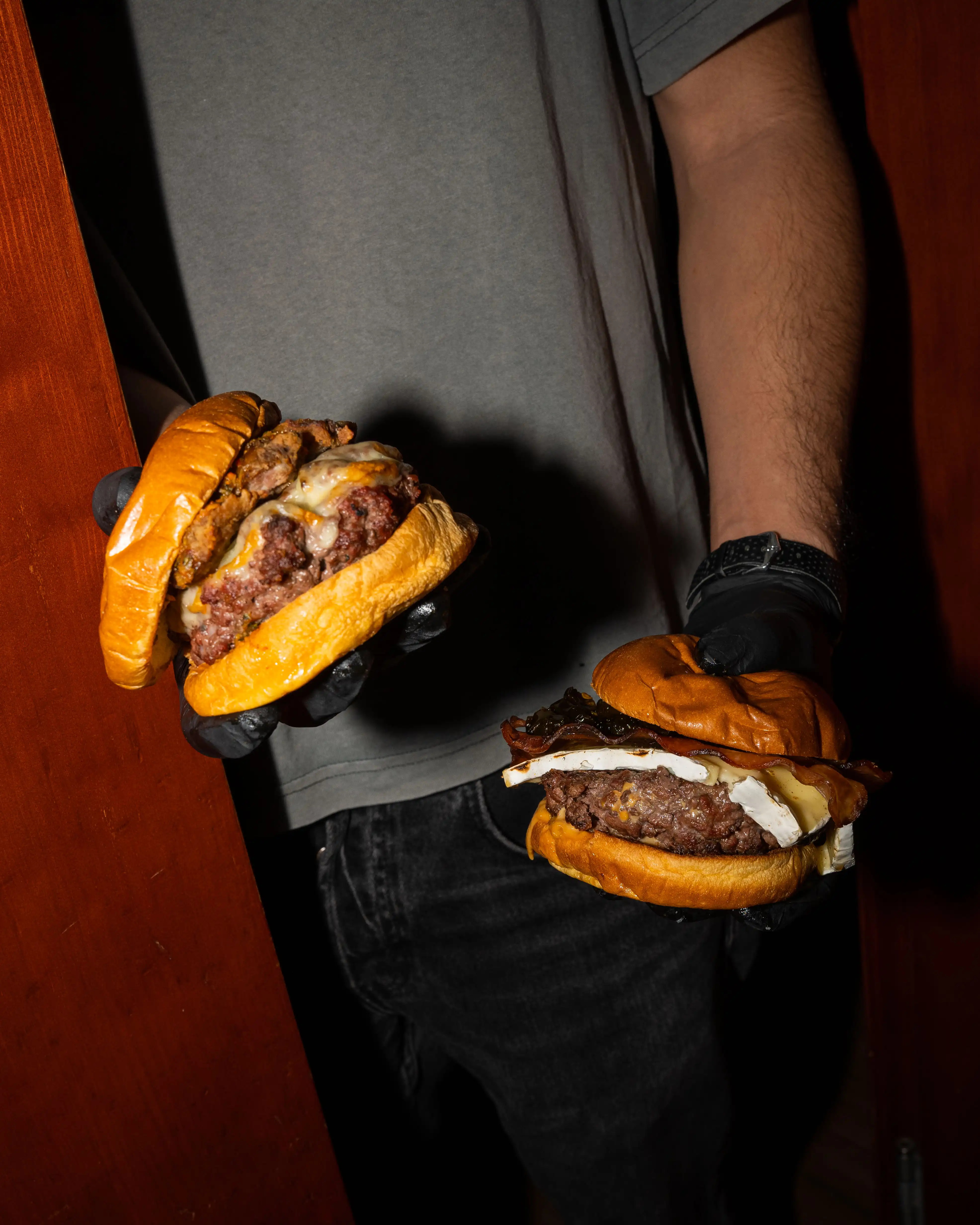 Dos hamburguesas de BURMET sostenidas por miembros del equipo
